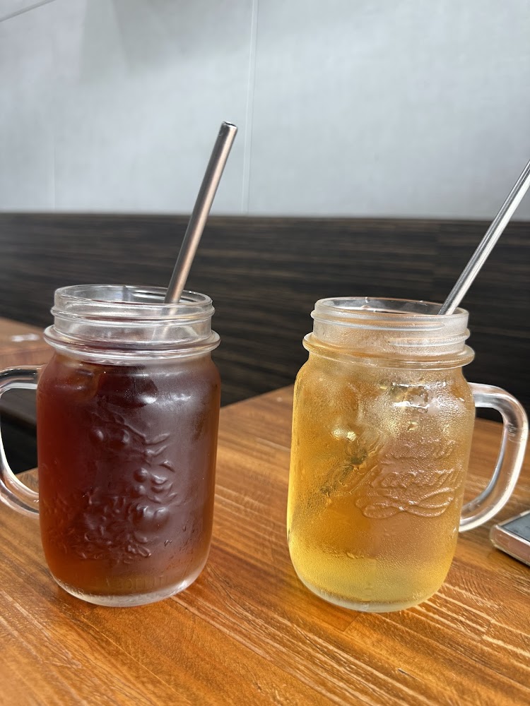 兩杯透明玻璃杯飲品，深色和淺色飲料中有冰塊與金屬吸管