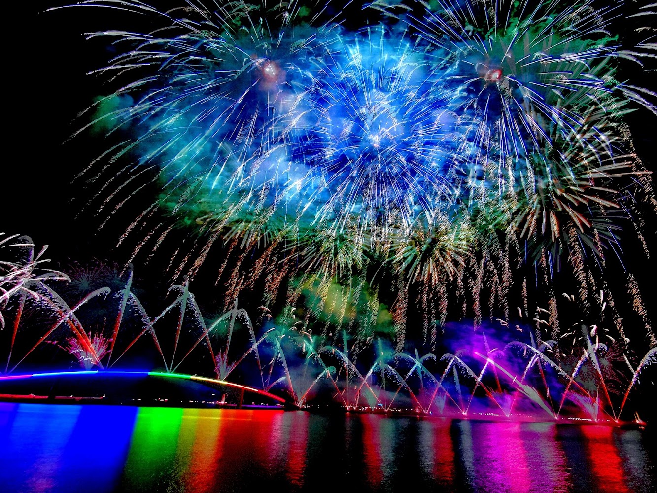 夜空中五彩煙火綻放，倒映在水面上。