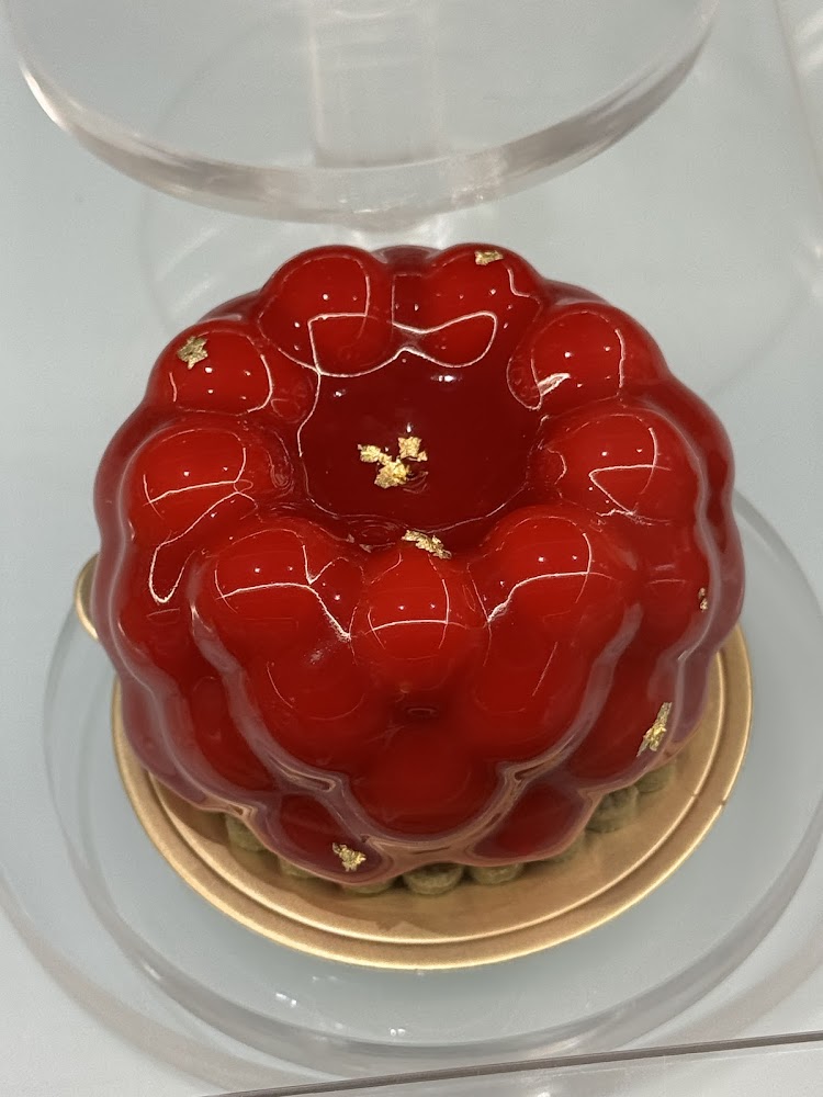 紅色鏡面甜點點綴金箔，底部有綠色餅皮