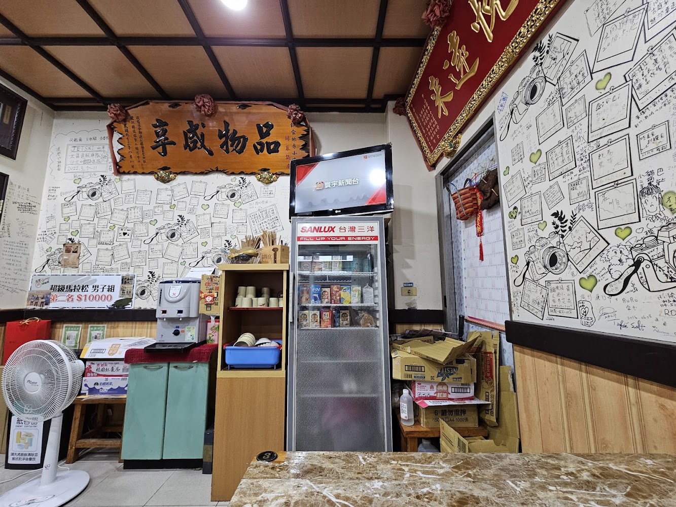 餐廳角落有飲水機冰箱電視與大量留言裝飾