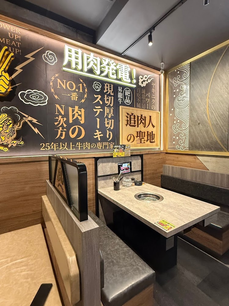日式燒肉餐廳包廂座位，桌上有內嵌烤爐，牆面有日文與中英文裝飾