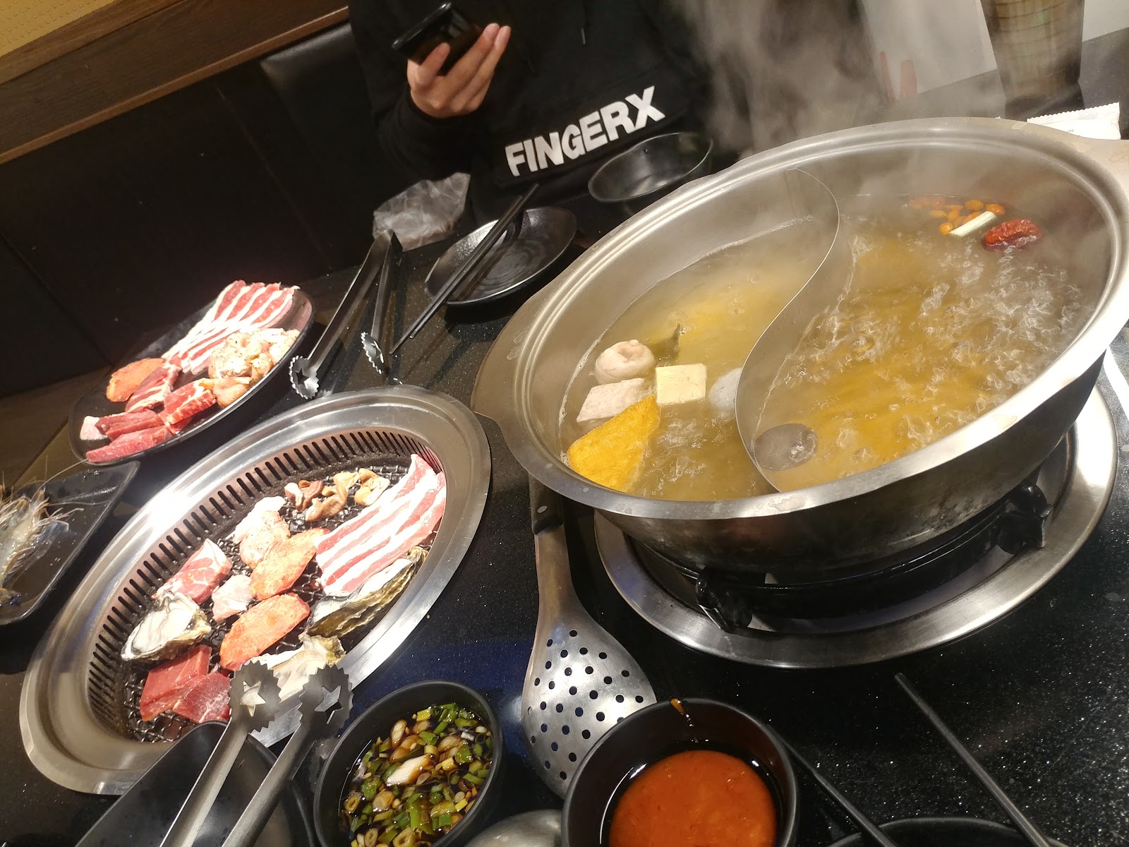 西門町周邊餐廳桌上的燒烤與火鍋，鐵板烤肉搭配金黃湯底火鍋