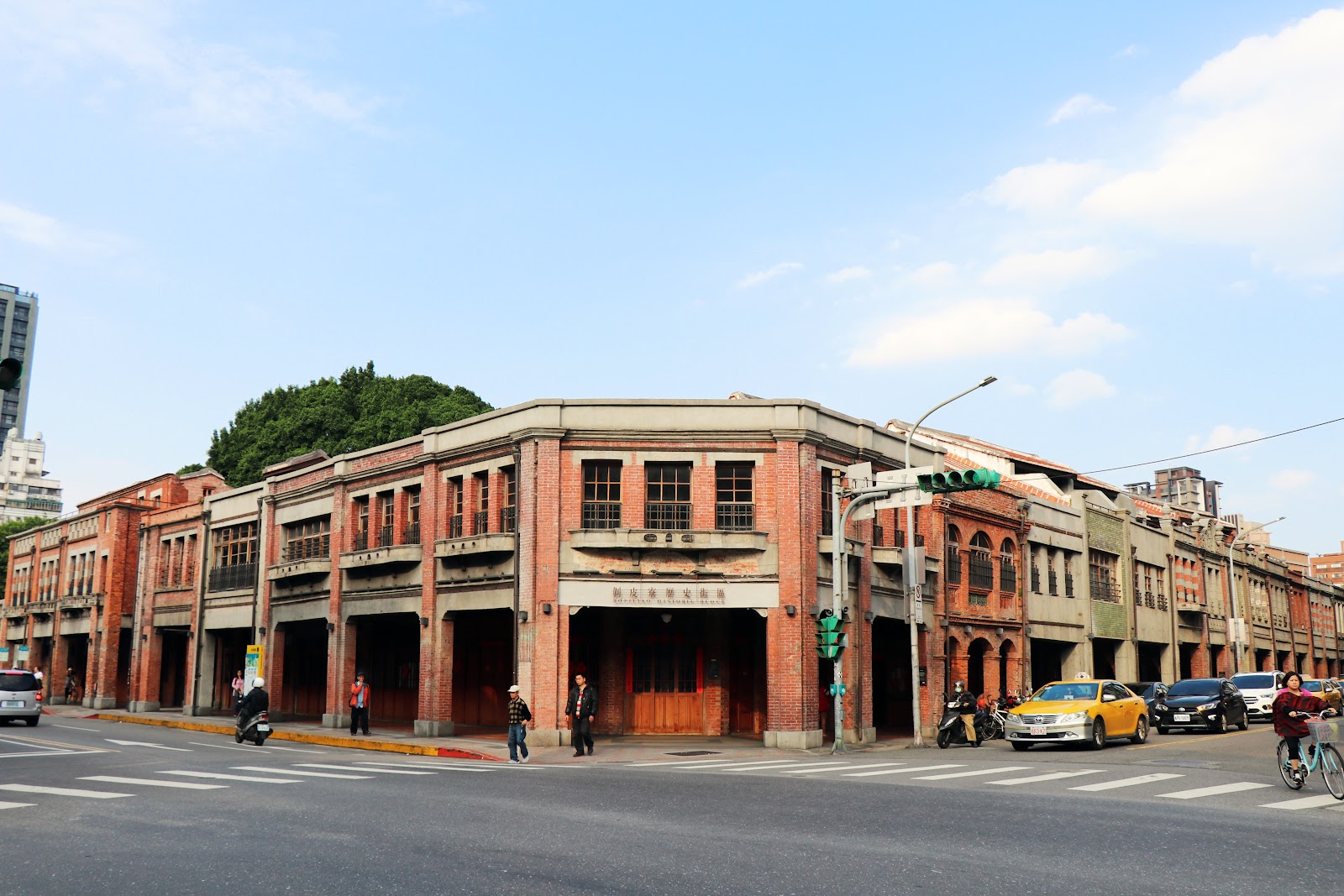 剝皮寮歷史街區街角建築全景，日治時代紅磚巴洛克拱廊建築立面，街道上有行人與車輛