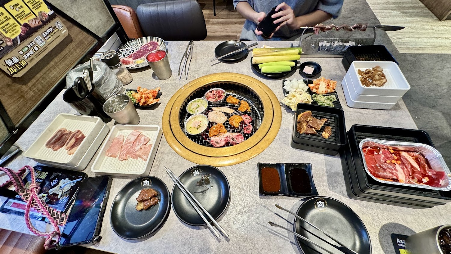 一桌豐富的燒肉套餐，有各種牛肉、醬料、蔬菜配料和韓式小菜