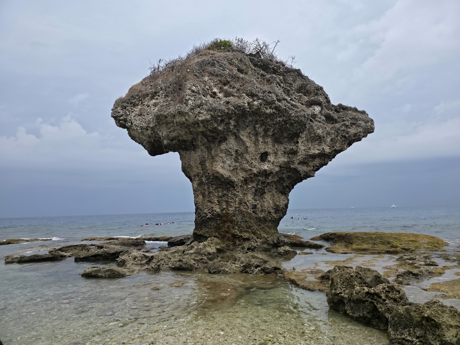 小琉球花瓶石近拍，底細頂寬的珊瑚礁岩，海藍背景
