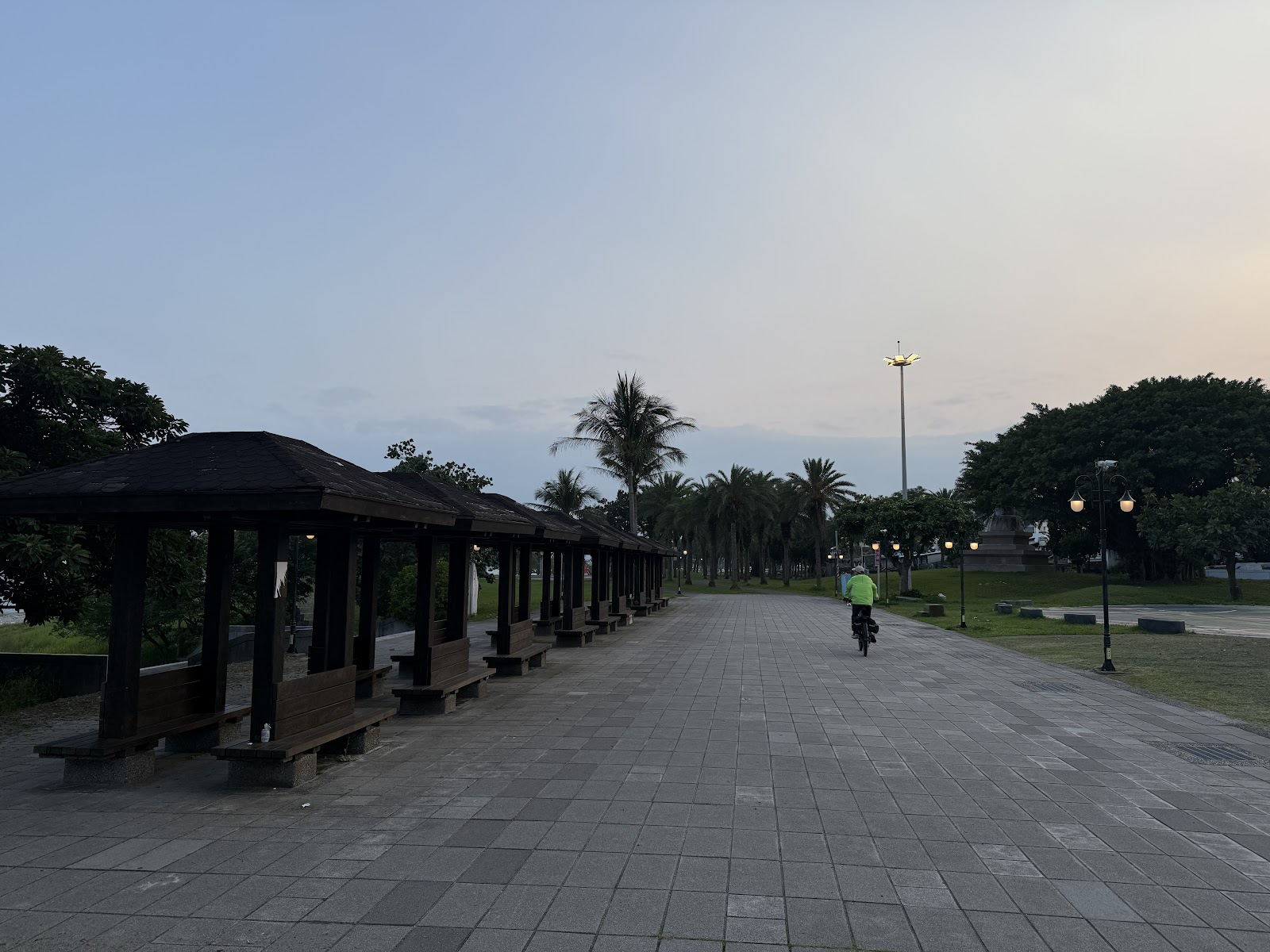 北濱公園黃昏木造涼亭長廊，騎自行車的人，椰子樹