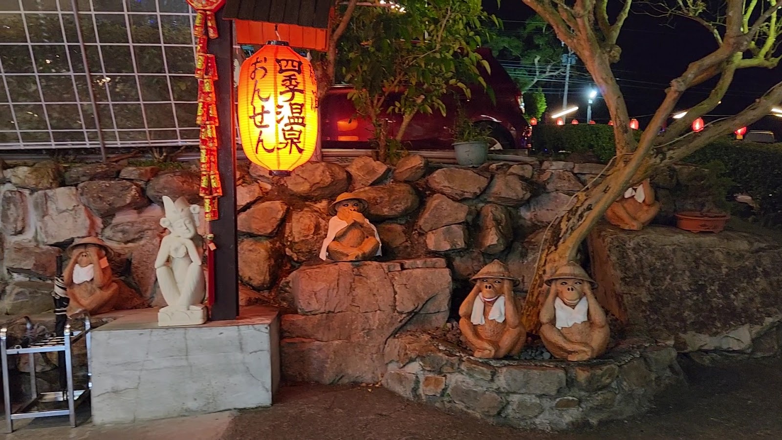 礁溪四季溫泉夜間入口，橘紅大燈籠和戴斗笠猴子石雕