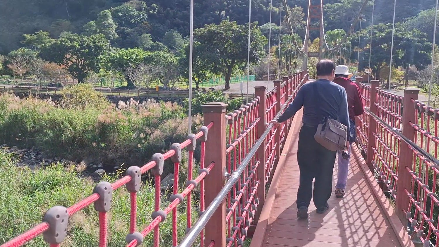 山林中的紅色吊橋,旅人步行其上進入園區