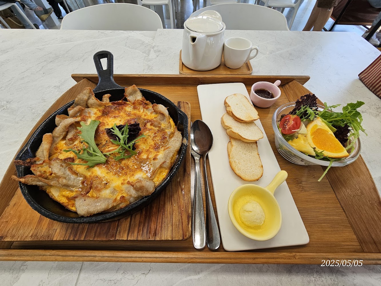 鐵鍋料理、麵包片、沙拉、水果以及茶壺杯組的早午餐