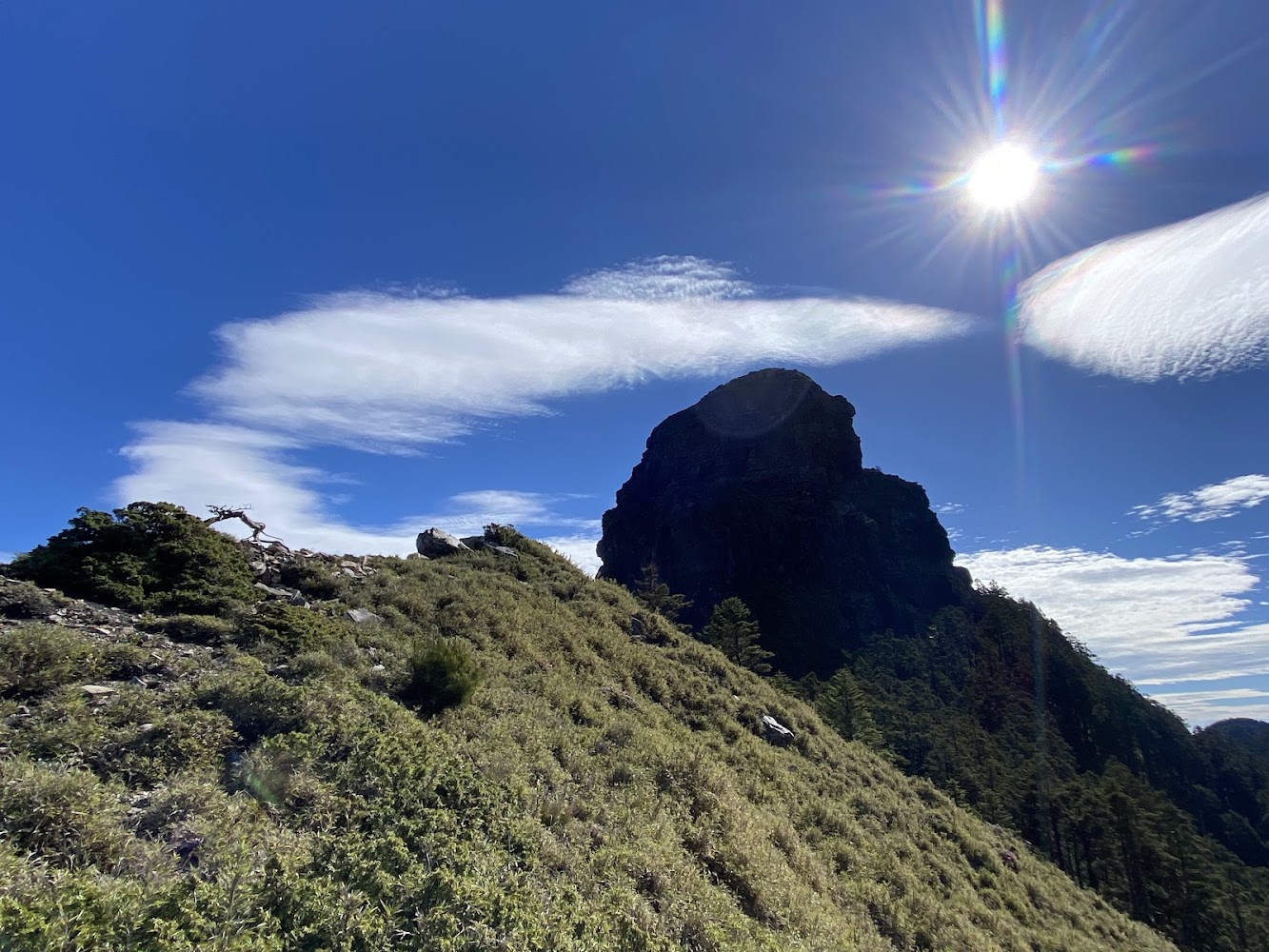 陽光照射下山頂繚繞雲朵的山峰景色