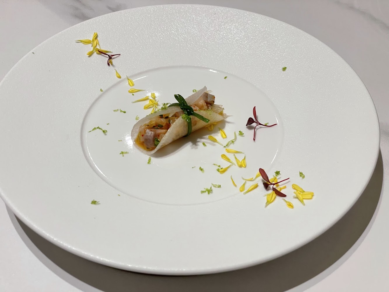 精緻卷餅前菜搭配花瓣與綠色香料點綴，擺盤細膩
