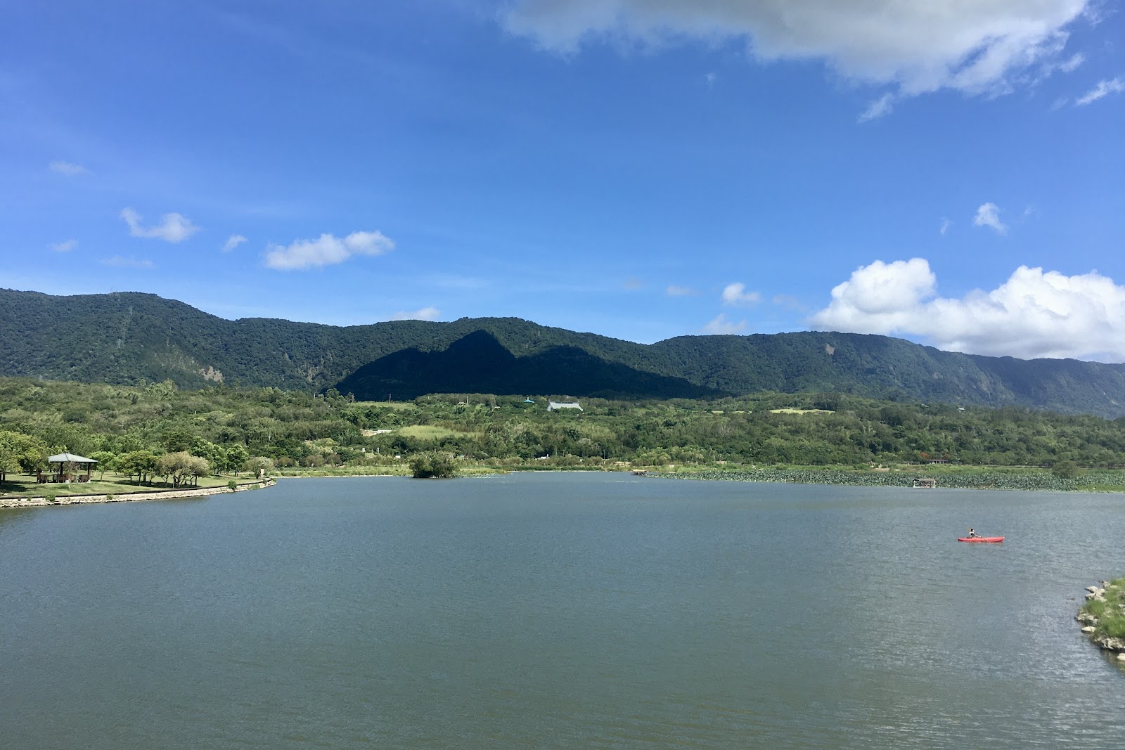 大坡池湖面廣闊藍天白雲紅色獨木舟背景綠山涼亭台東池上一日遊