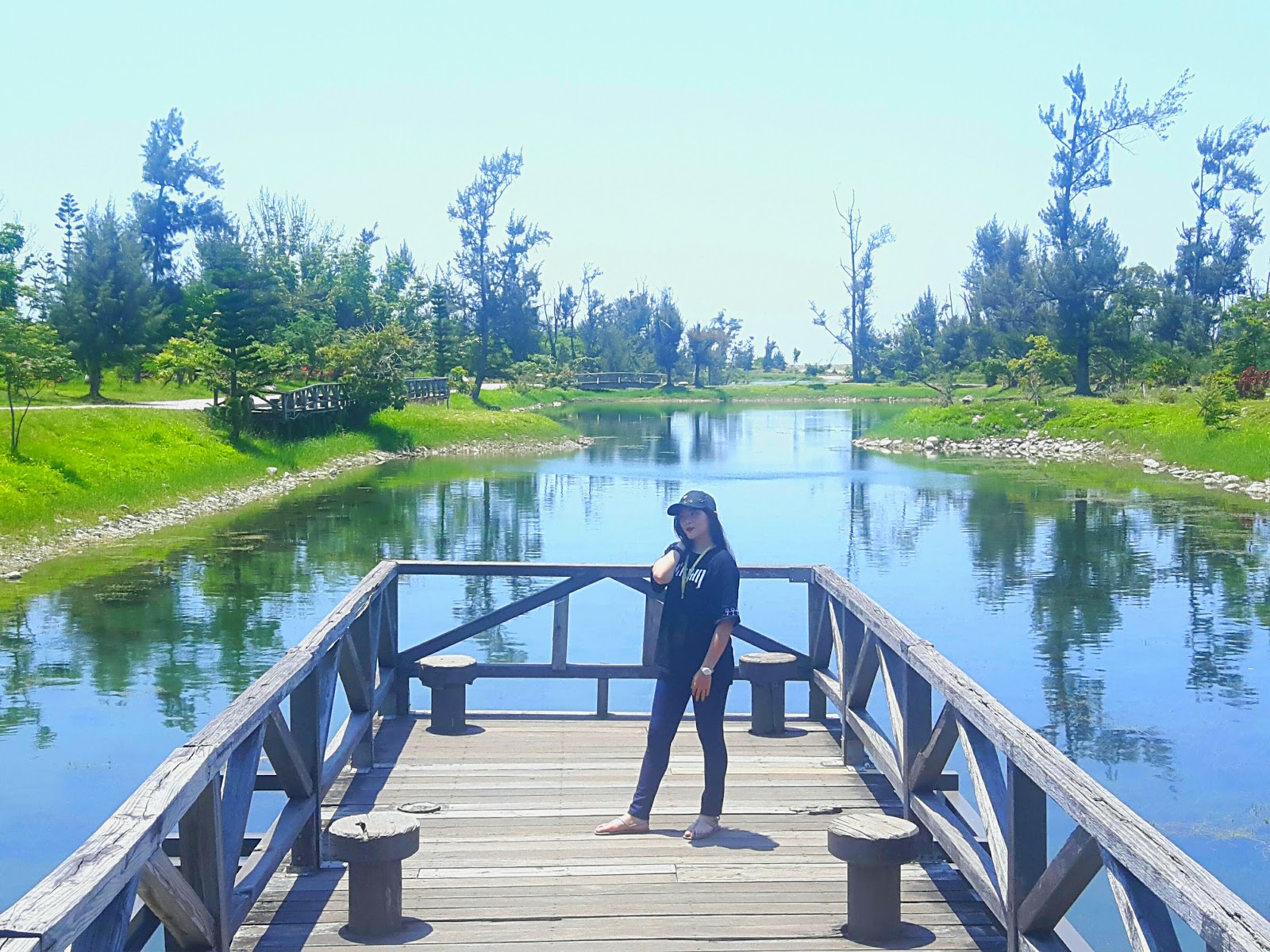 女遊客站於台東森林公園木棧橋上欣賞美景湖面倒映木麻黃林