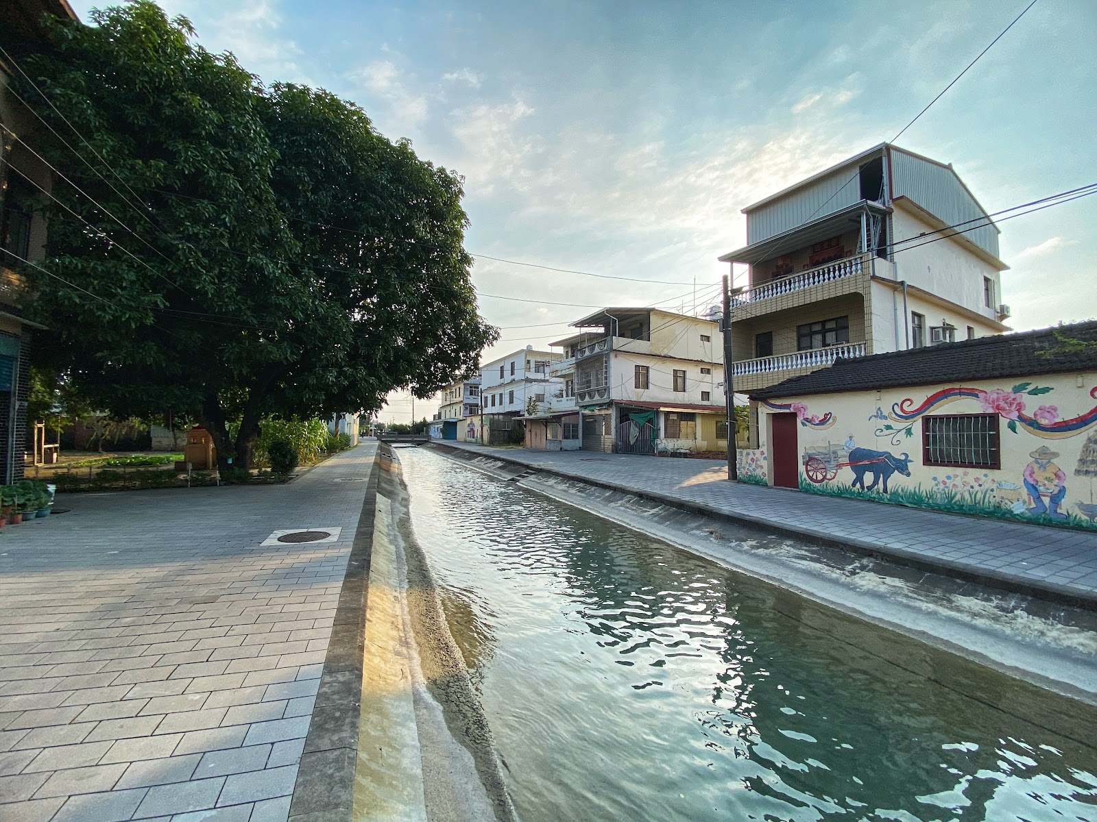 美濃水圳渠道流水，石板步道，右側有客家農耕彩繪壁畫