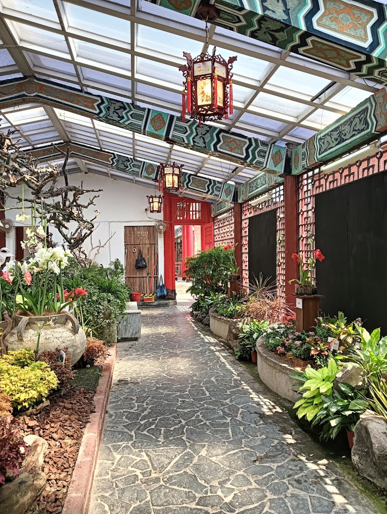 中國風格長廊屋頂有彩繪樑柱與傳統燈籠，兩旁擺放許多花草植物