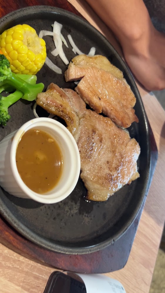黑色餐盤上有三塊煎肉、玉米、花椰菜、洋蔥絲與蘑菇醬。