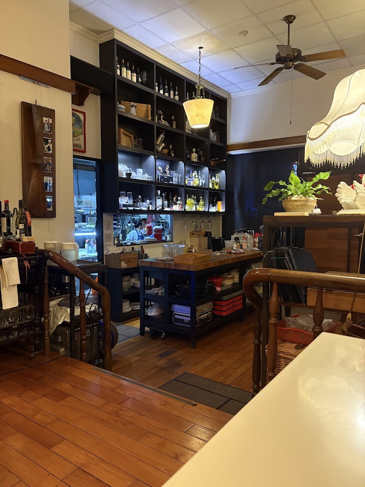 餐廳吧台與開放式廚房，牆上有酒品展示櫃、玻璃杯和餐具，並有綠色盆栽點綴