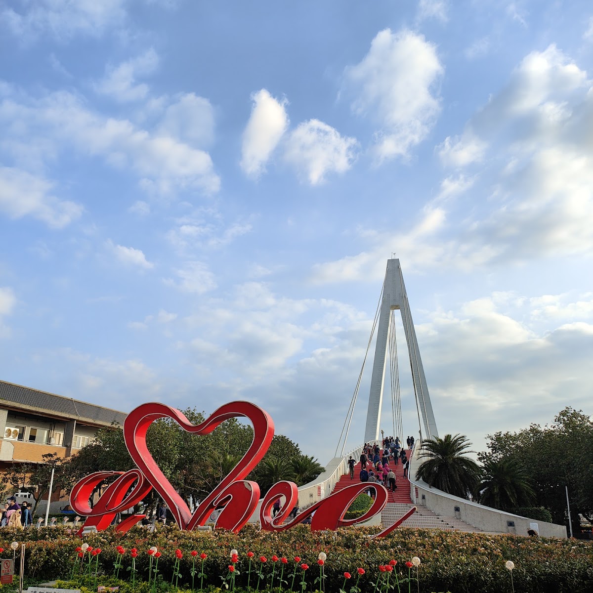 漁人碼頭情人橋入口廣場白天，紅色Love愛心裝置，人群走上橋台階