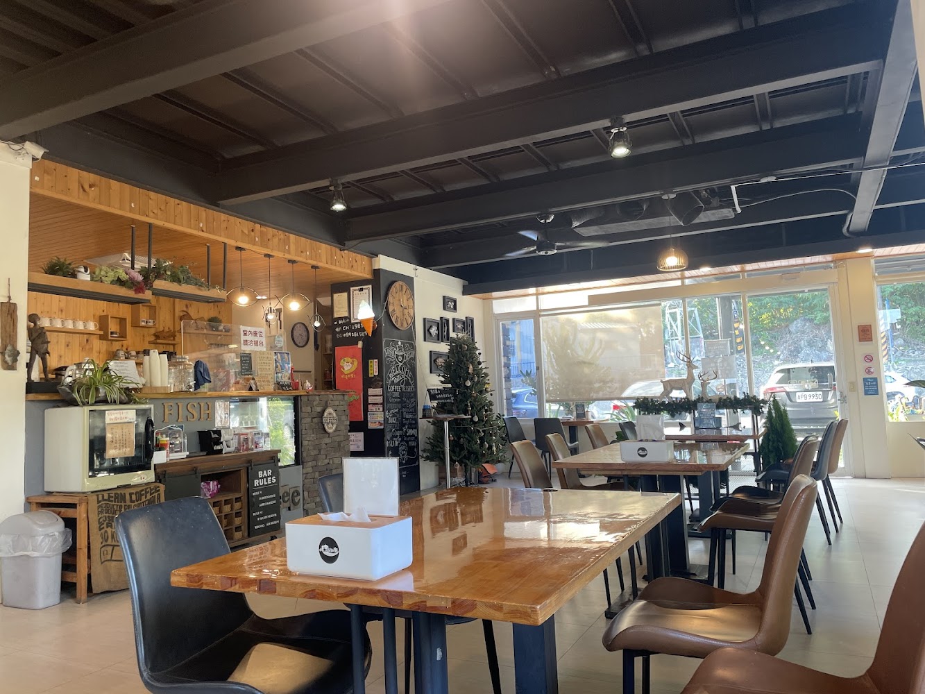 裝潢溫馨的咖啡廳，內有木質餐桌椅、吧檯、裝飾植物和聖誕樹，室內明亮