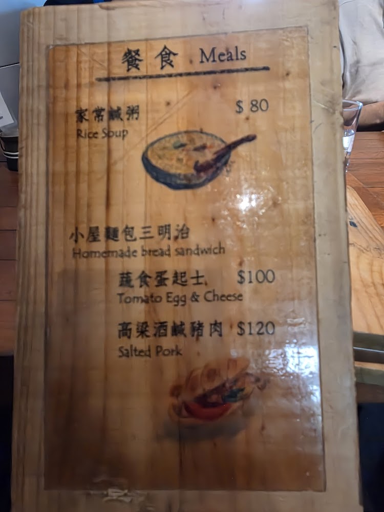 這張照片是一本木製菜單，主要提供家常鹹粥、手工麵包三明治、蕃茄蛋起士和高粱酒鹹豬肉等四種餐點，並標示價格和菜品插圖。