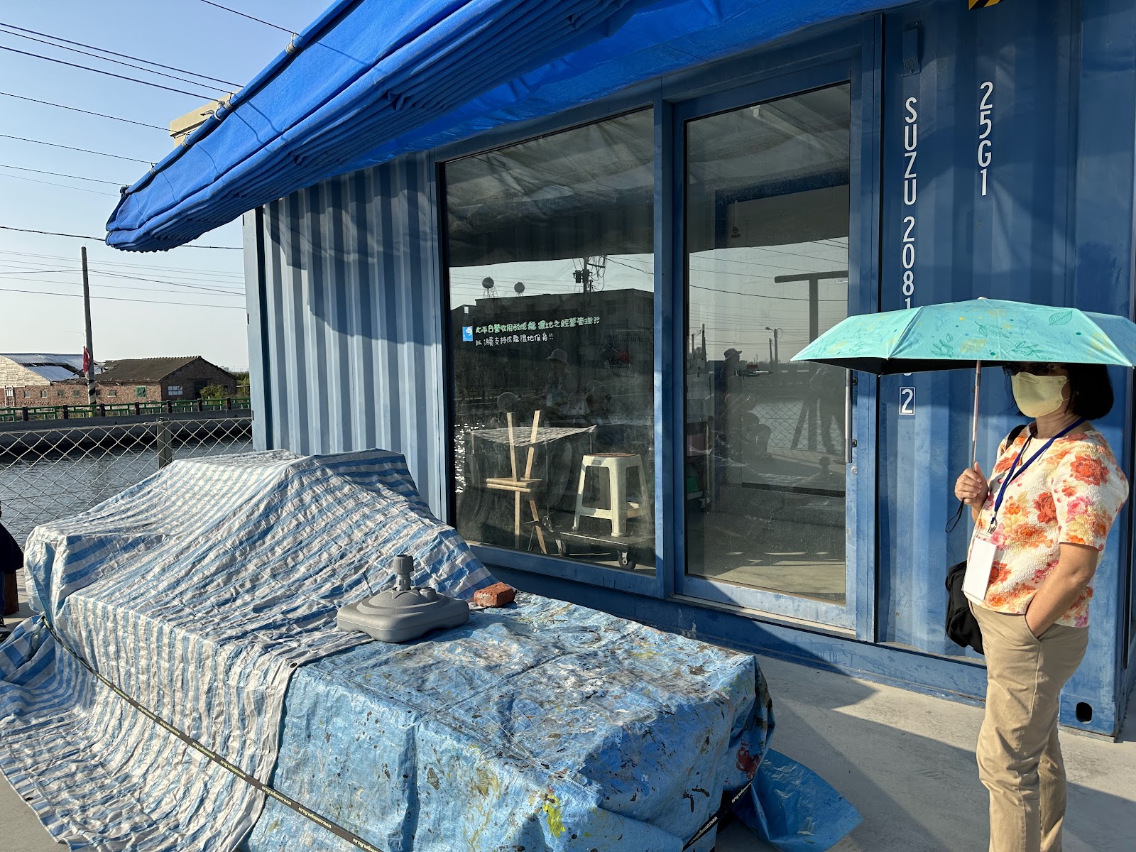 成龍濕地藍色貨櫃改裝藝術展示空間，前方有海浪造型裝置