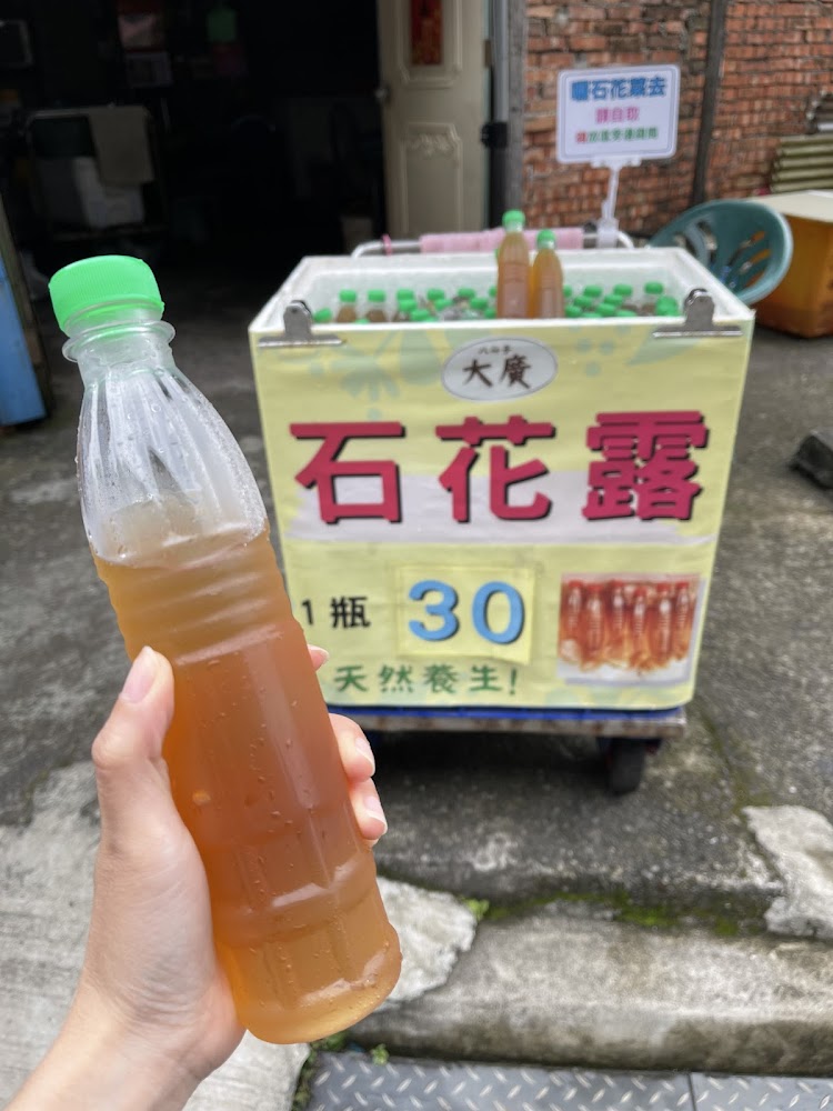手拿石花露瓶裝飲料,後方冰箱可見一瓶30元標示