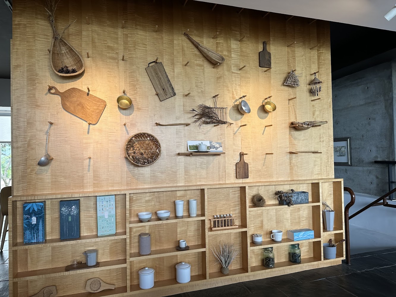設計感十足的木質展示牆，上方裝飾竹籃、切菜板、金屬器皿與自然素材