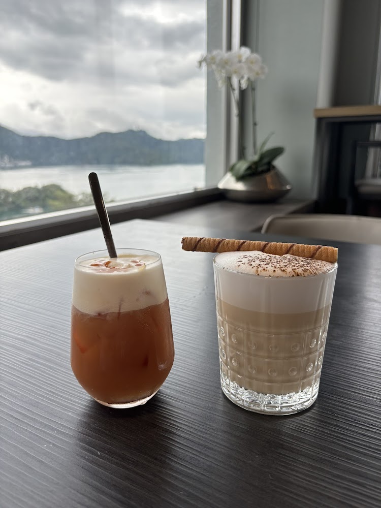 兩杯飲品與白色蘭花襯著窗外湖景