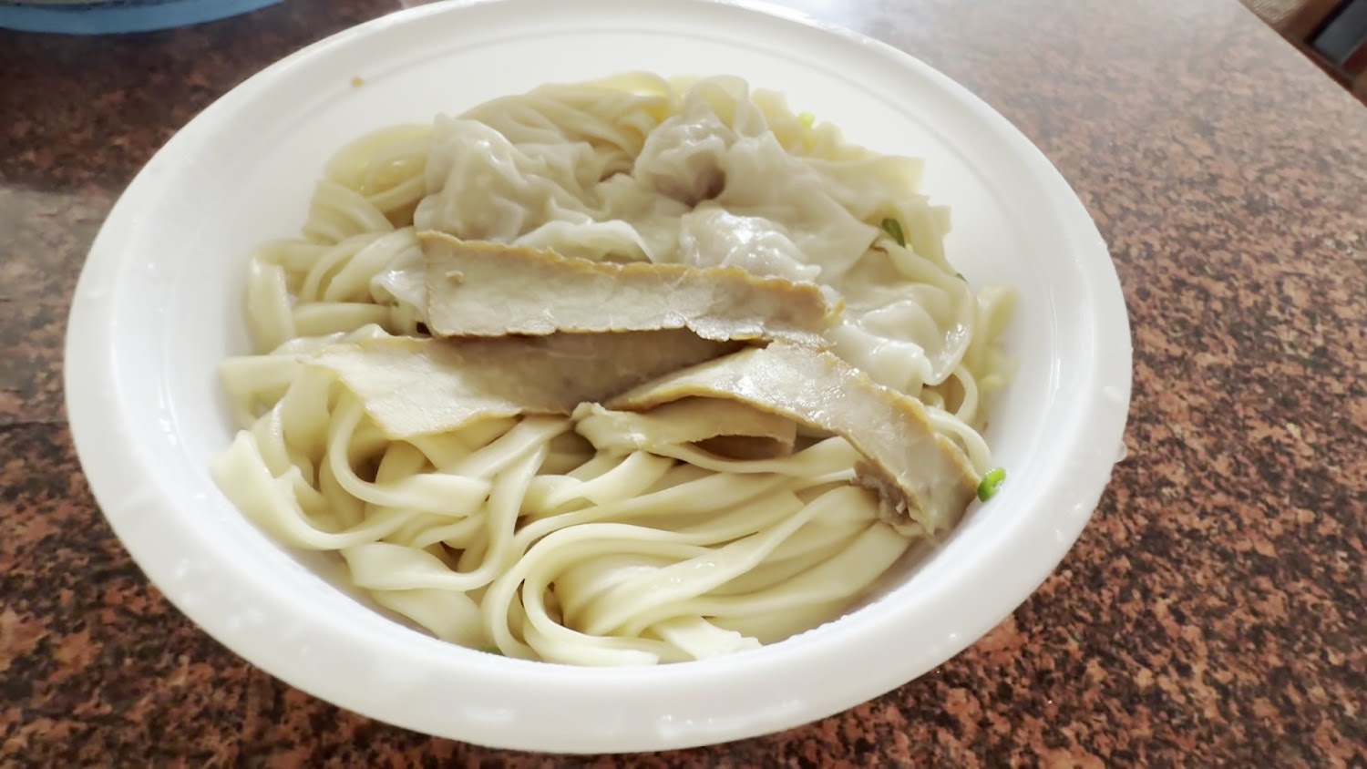 肉片與餛飩麵特寫，白色大碗中有寬麵與多樣配料