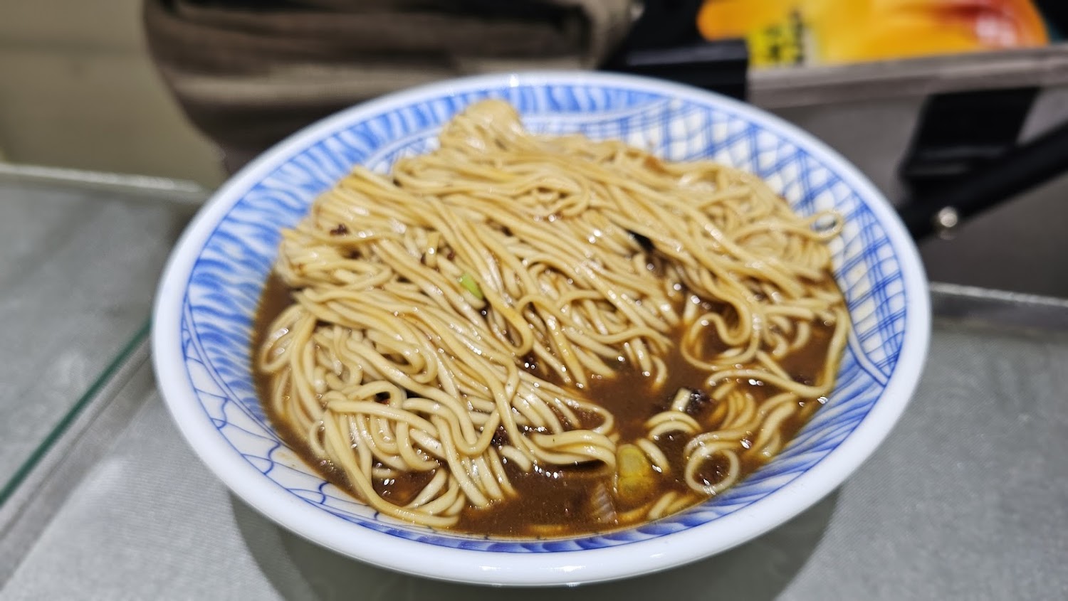 一碗盛有湯汁的麵條，麵條細長，湯色深褐
