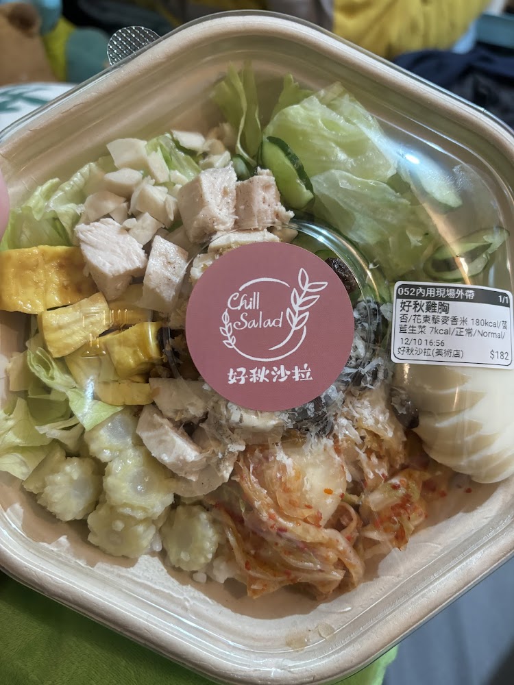 這張圖片是一份沙拉餐盒，內含雞胸肉塊、玉子燒、萵苣、小黃瓜、泡菜以及蛋和沙拉醬，食材豐富且色彩繽紛，看起來健康美味。