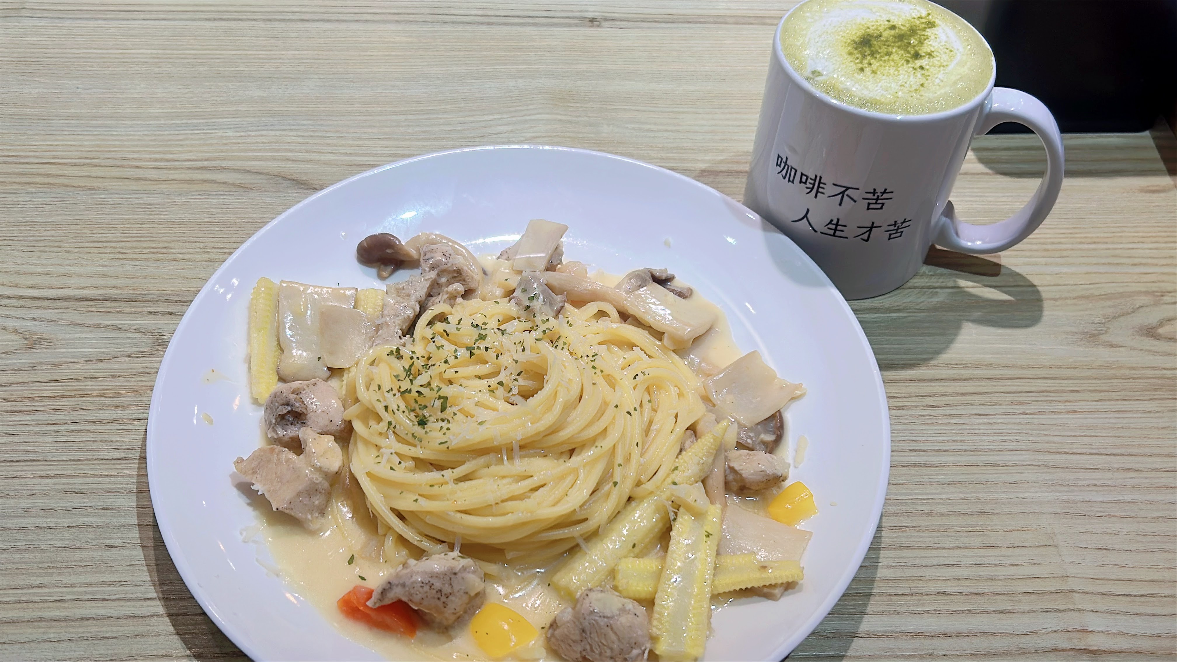 奶油雞肉義大利麵搭配拿鐵，上面撒有抹茶粉