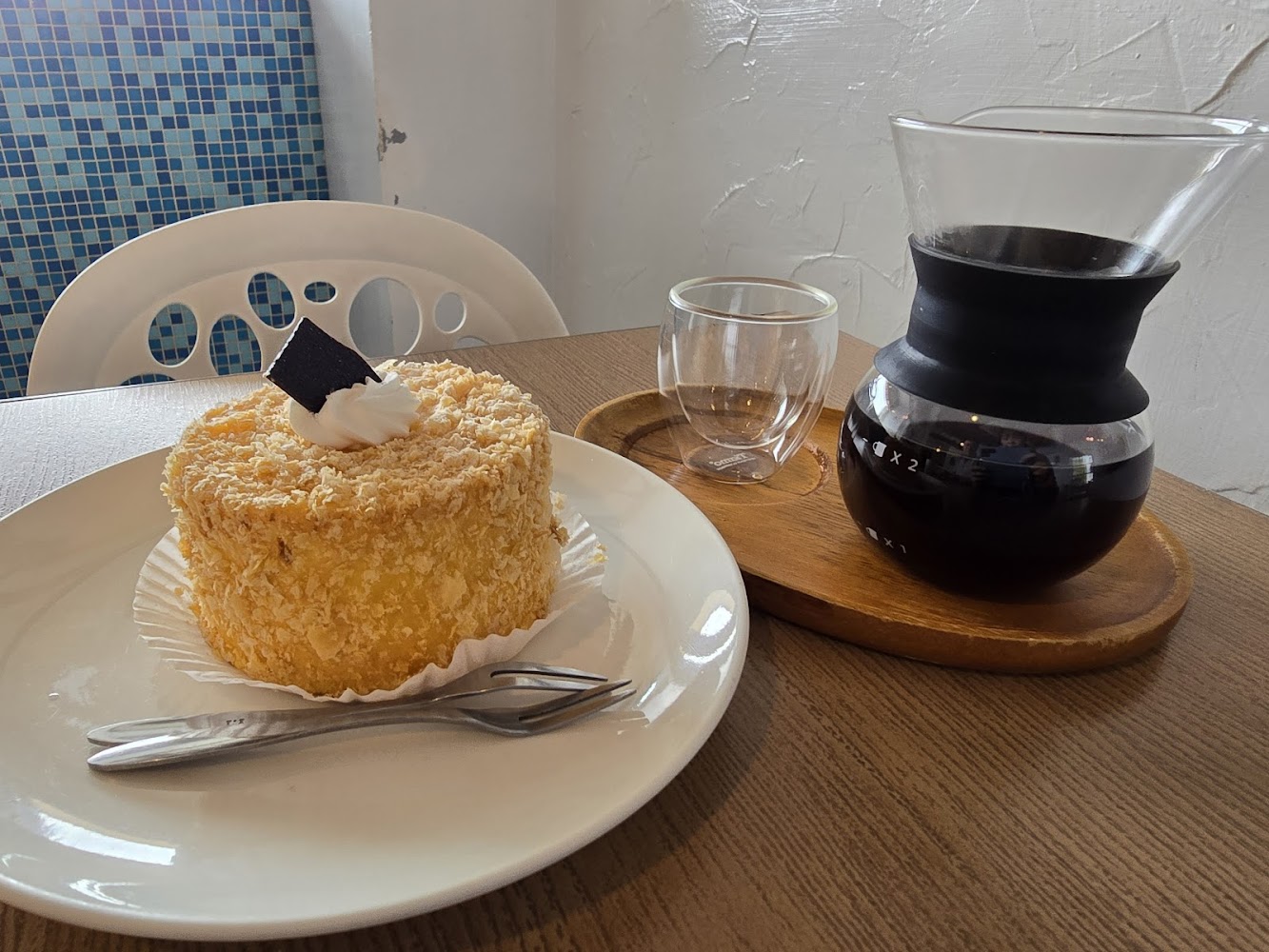 蛋糕、黑咖啡壺與玻璃杯擺放在木質桌面上