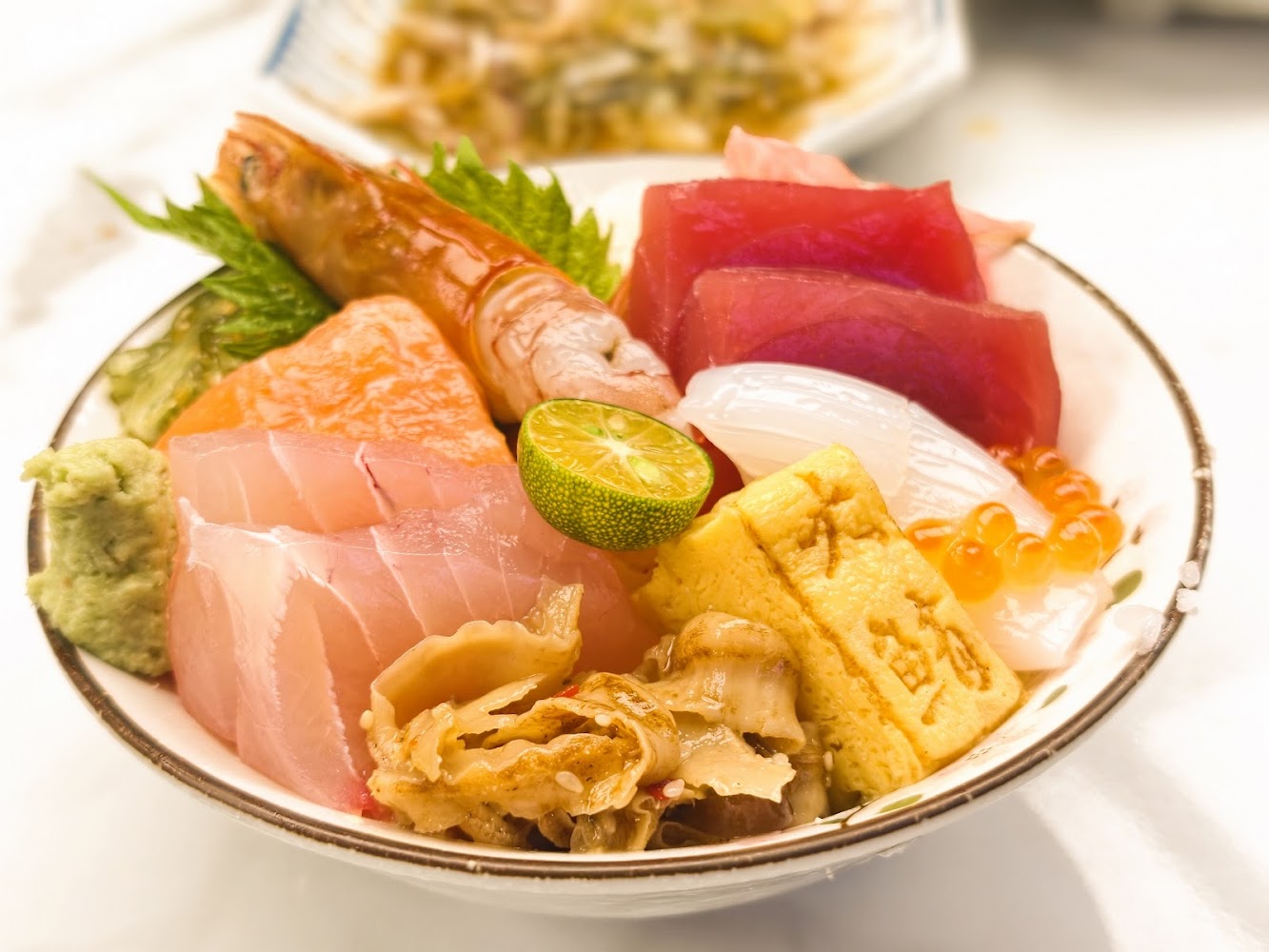 海鮮丼飯配料豐富，包含鮪魚、鮭魚、甜蝦與魚卵，色彩鮮明。