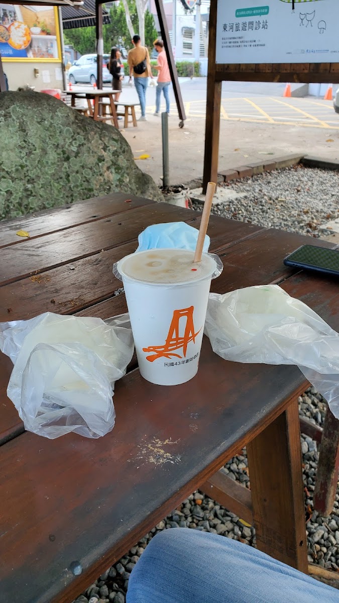纏記舊街東河包子紙袋與飲料，兩個切開的包子露出豐盛豬肉內餡