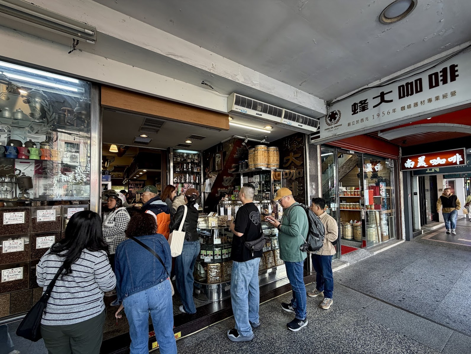 蜂大咖啡店門口，顧客站在店外挑選各式咖啡豆，招牌寫著創立1956年