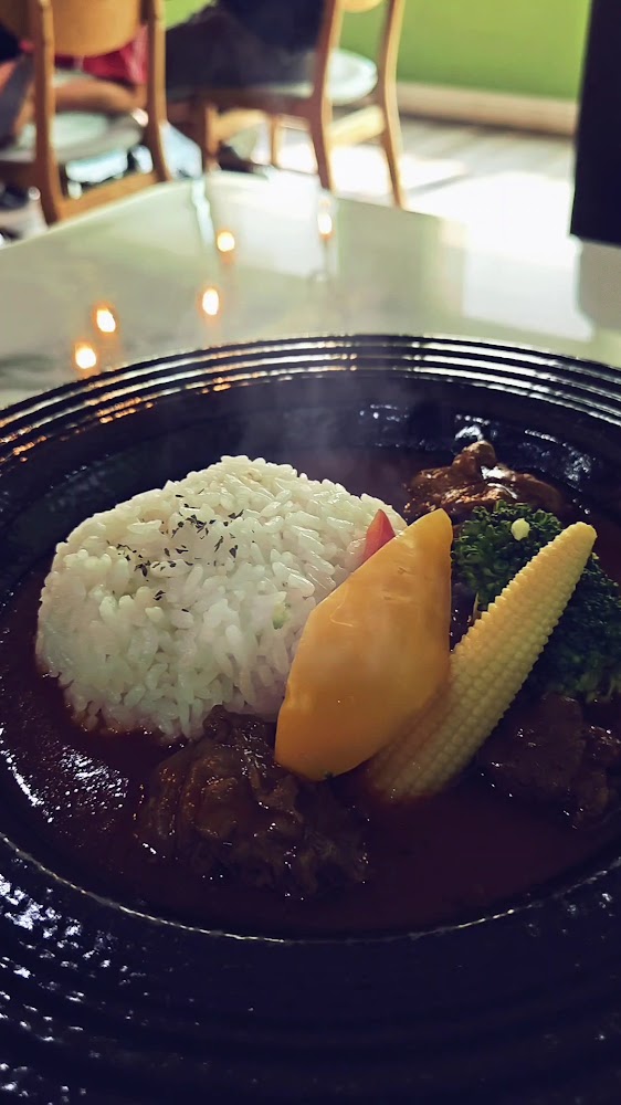這是一盤咖哩飯，包含白飯、咖哩醬、燉牛肉，配有玉米筍、花椰菜及南瓜等蔬菜，擺盤精緻，色香味俱全。