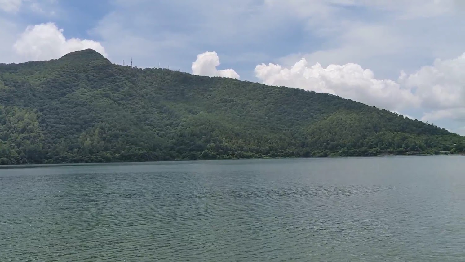 山腳下平靜湖水與白雲飄過的自然景致