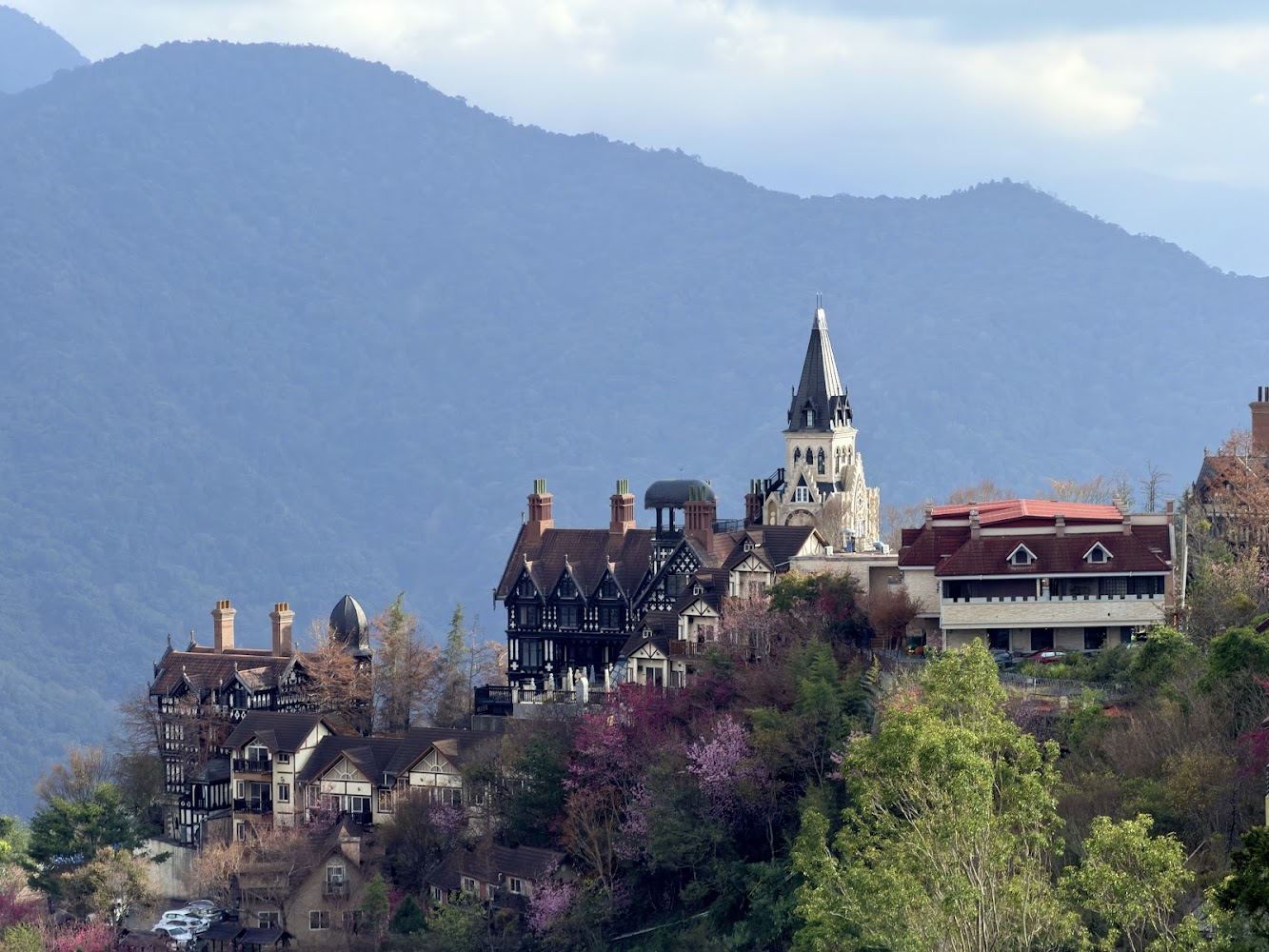 歐式建築群與前方樹林花木及壯麗山巒