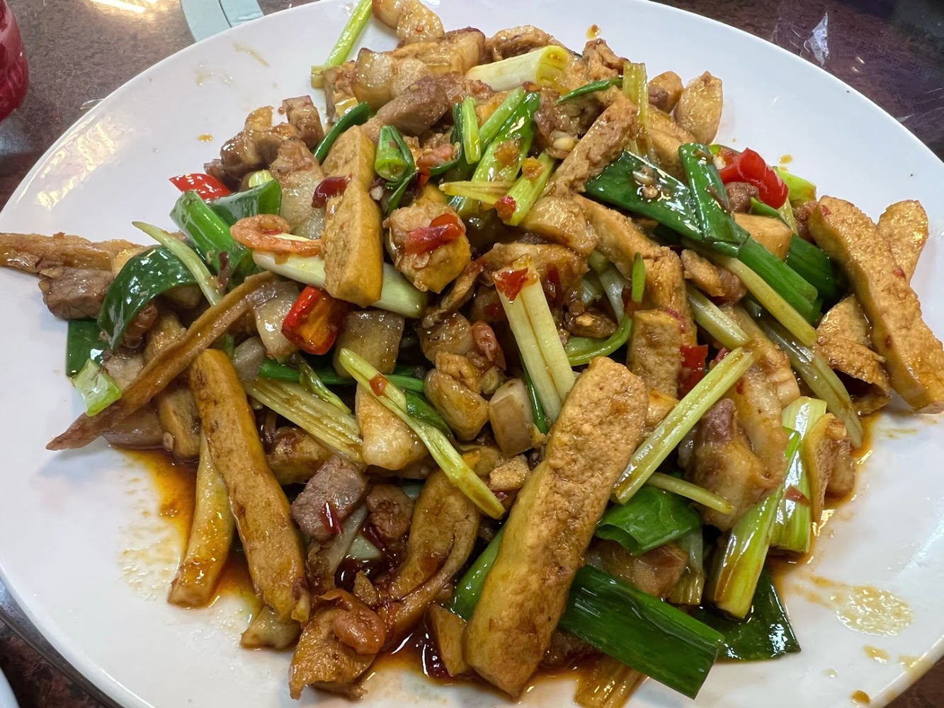 一道熱炒料理，主要包含豆干、蔥段、辣椒、豬肉等食材