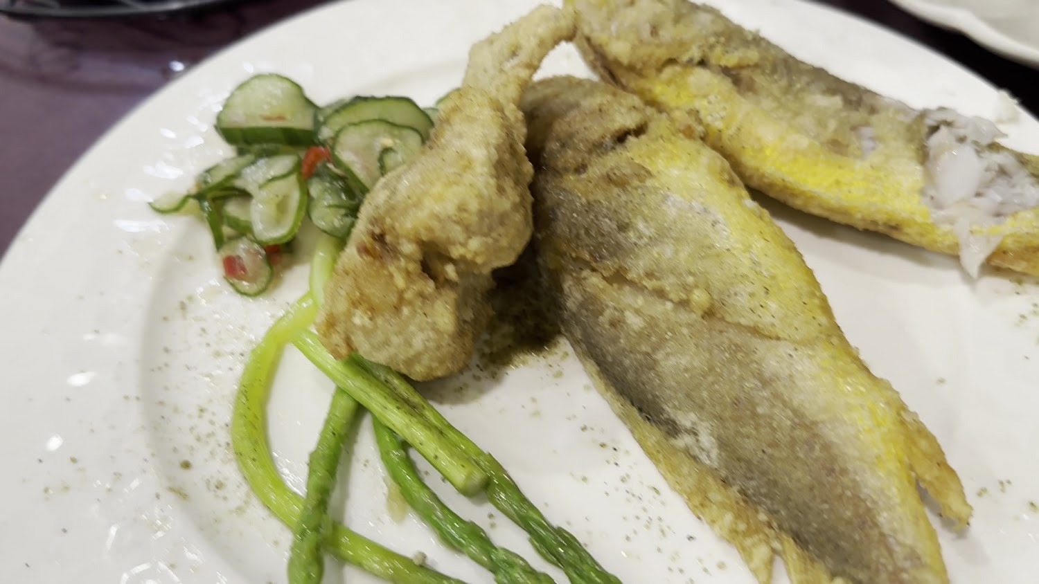 這張圖片主要呈現一盤炸魚搭配小黃瓜沙拉與四季豆，魚肉酥脆金黃，配菜清爽，擺盤簡單美觀，是一道中式或台式的家常料理。