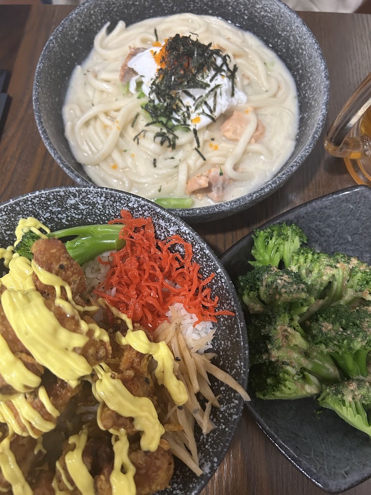 這張圖片主要有三樣食物：一碗奶油烏龍麵，上面有溫泉蛋與海苔；一碗日式炸雞蓋飯，搭配蔬菜和醬汁；以及一盤涼拌花椰菜。