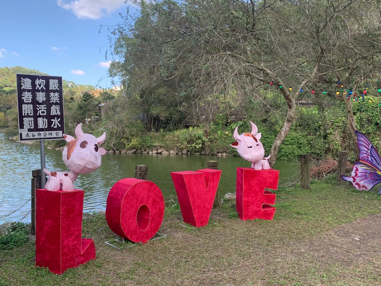 大型紅色LOVE字母裝置藝術旁有湖水與綠樹景致