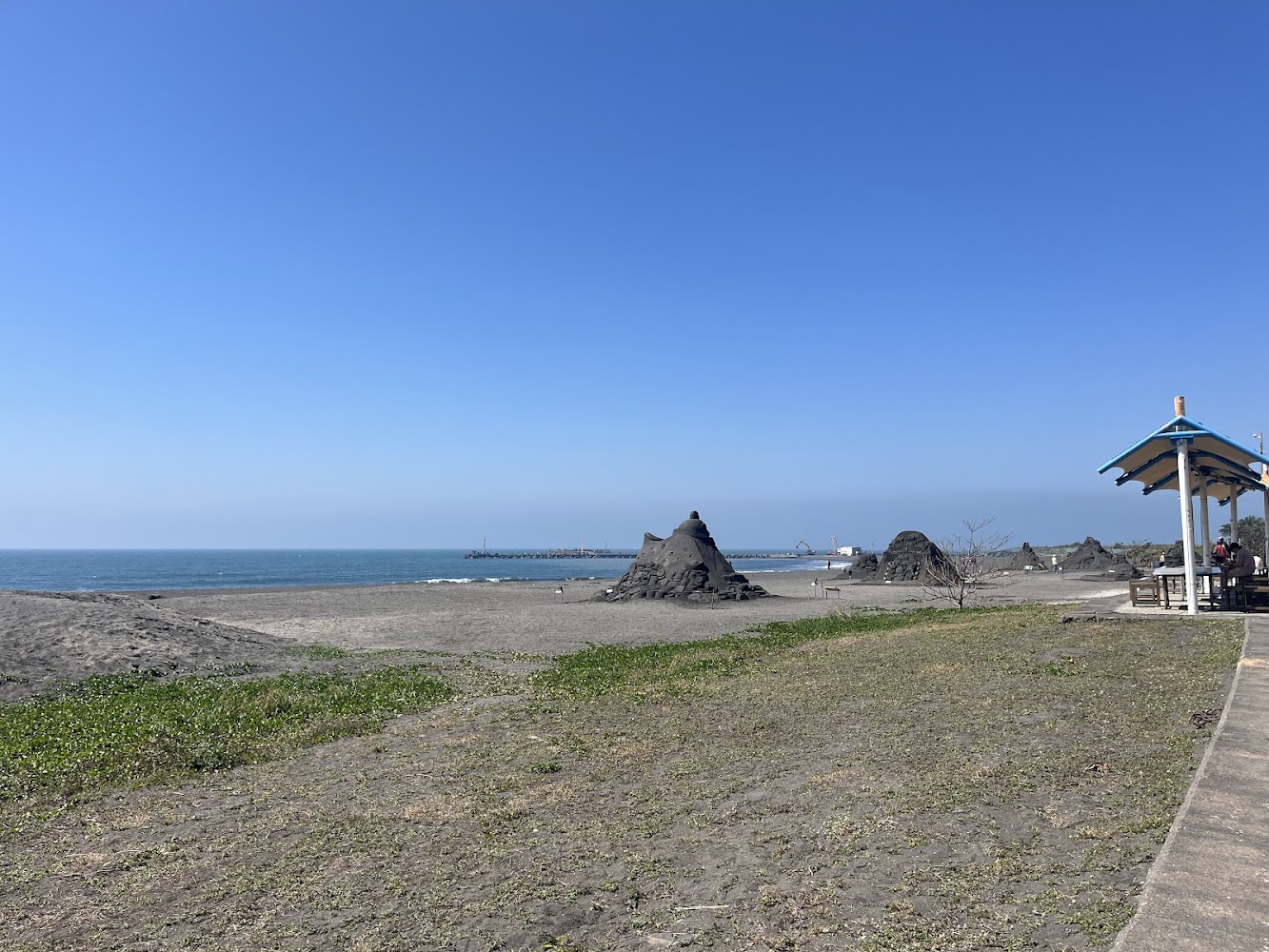 寬廣沙灘上的大型黑色沙雕與晴朗海景