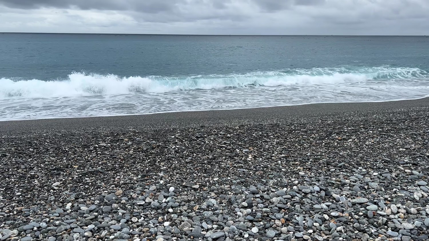 前景各色圓潤鵝卵石與海浪拍岸的七星潭海灘