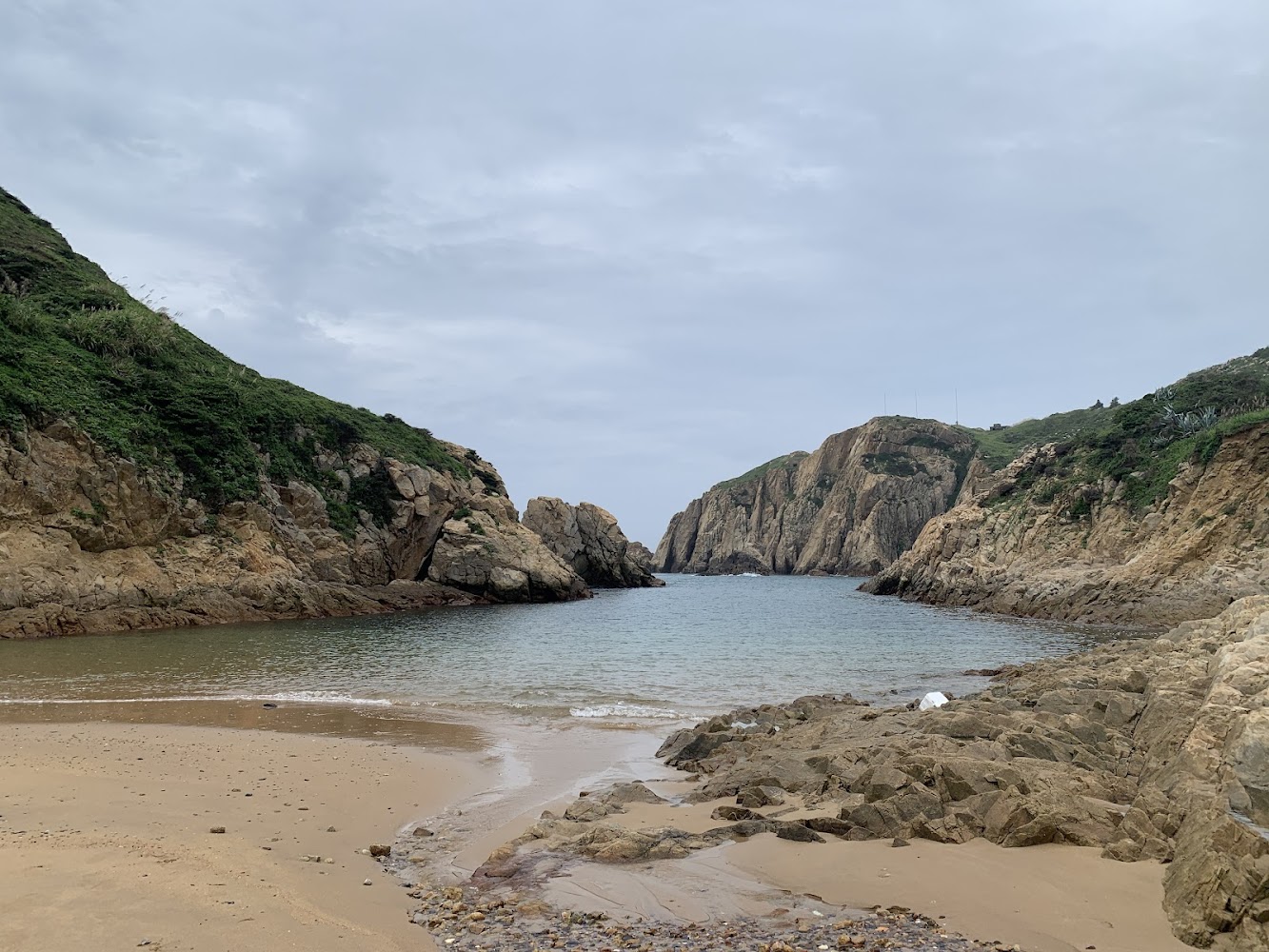神祕小海灣沙灘與兩側綠色山崖