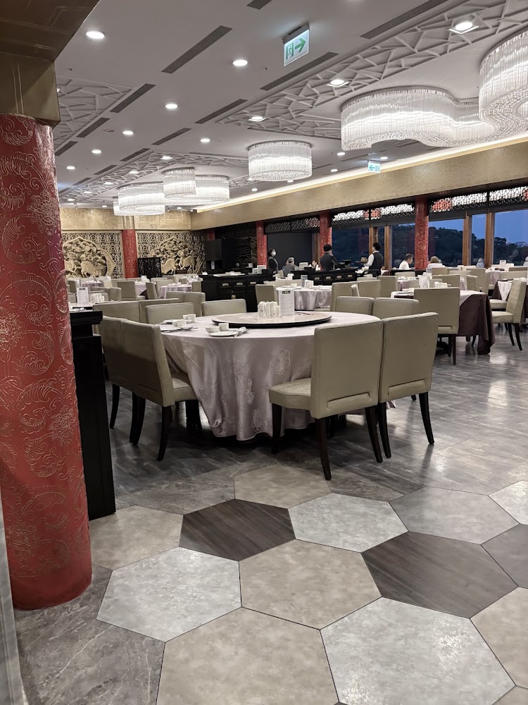 裝潢典雅的中式餐廳,室內有圓桌、舒適椅子、水晶吊燈與雕花柱子及壁飾