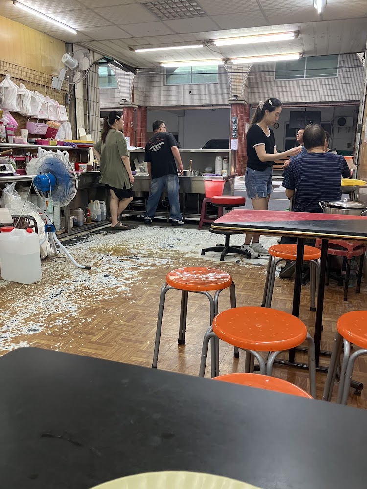 小吃店內有橘色圓椅與黑色桌子客人正在用餐