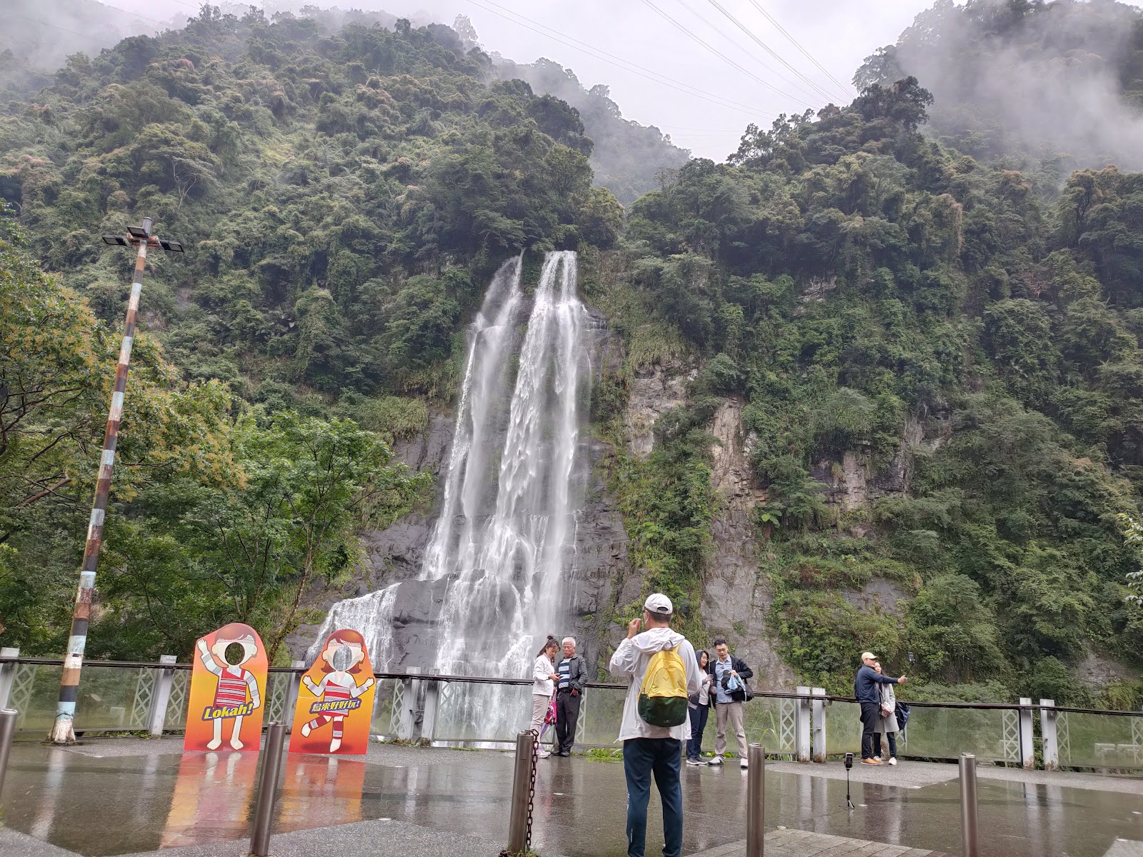 烏來瀑布壯闊全景，白色瀑流從山崖傾瀉而下，遊客在觀景台駐足
