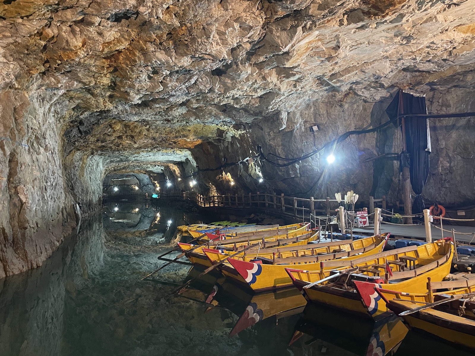 北海坑道搖櫓體驗，黃色彩繪木船停靠岩洞碼頭，水面映照燈光